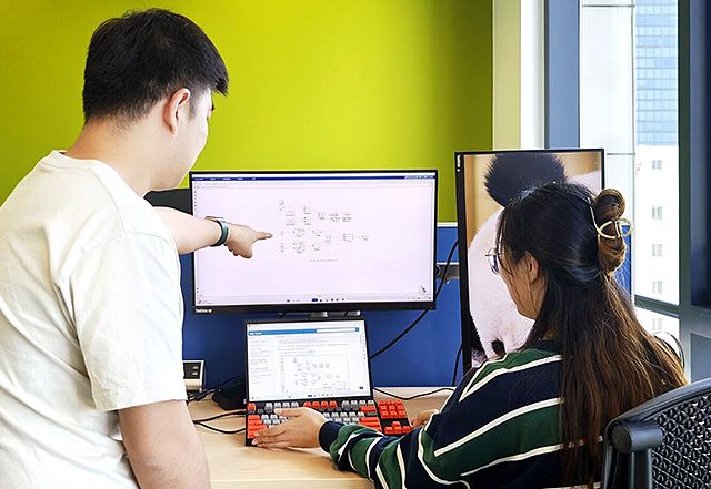 两位 mathworks 员工看着计算机屏幕,其中一人指向屏幕上的特定区域。